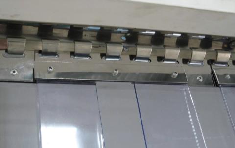 Detailed view of a mounted stainless steel hook-on track and plate system with overlapping clear PVC strips in an industrial setting.