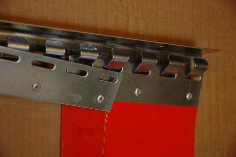 Angled close-up of a stainless steel hook-on track and plate system holding both red and clear PVC strip curtains against a wooden background.