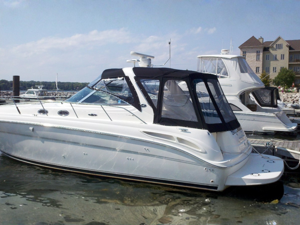 A white motor yacht at a marina featuring a black canvas enclosure with clear vinyl windows.