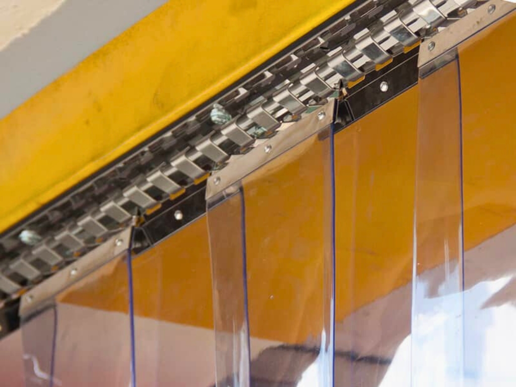 Close up of clear pvc strip curtains fixed to a metal hanging bracket.
