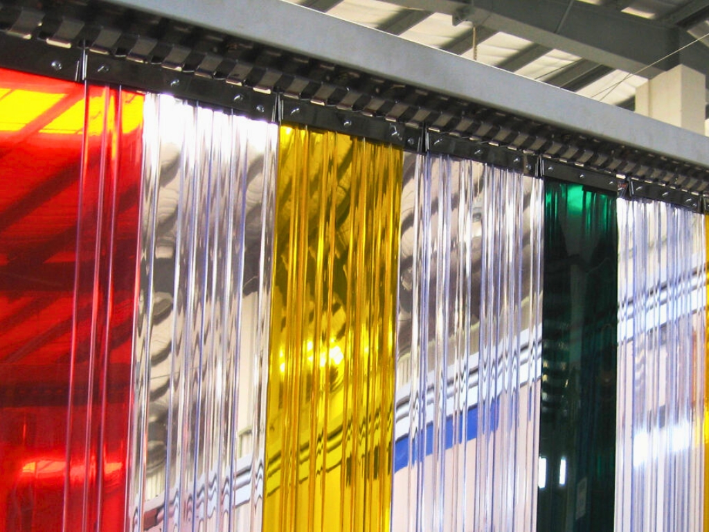 Colorful pvc strip curtains in red, clear, yellow, and green hanging from a rail.