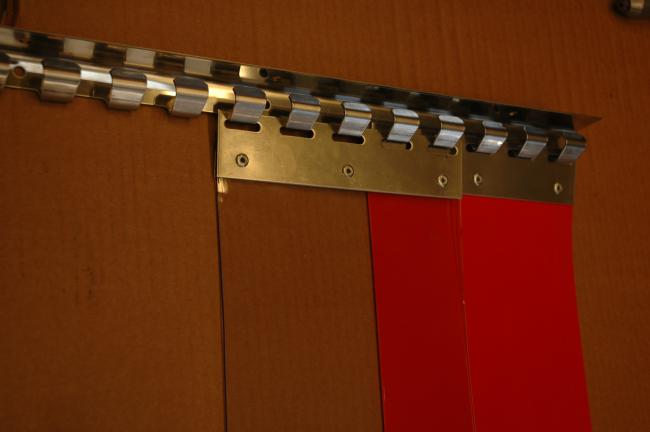 red and clear PVC strip curtains hanging from a metal hook-on rail system fixed to a wooden surface