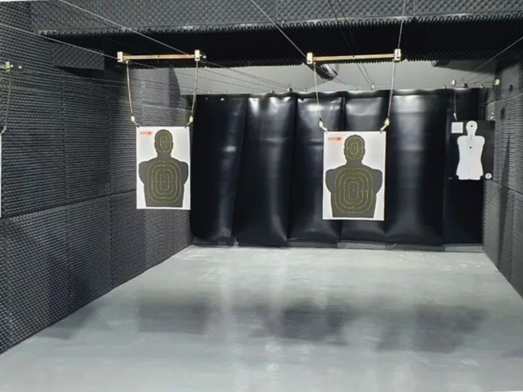 Indoor shooting range with black curtains and silhouette paper targets.