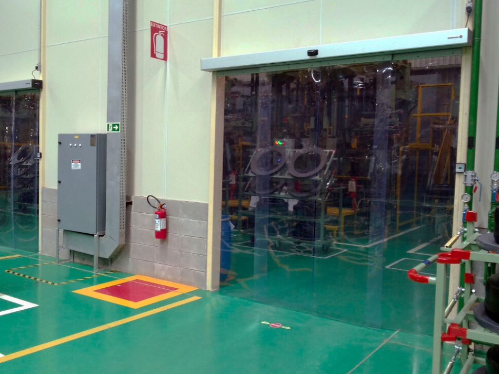 A large, see-through PVC curtain enclosure inside a warehouse.