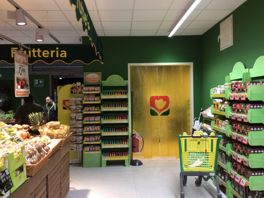 A yellow PVC strip curtain with a logo in a grocery store.