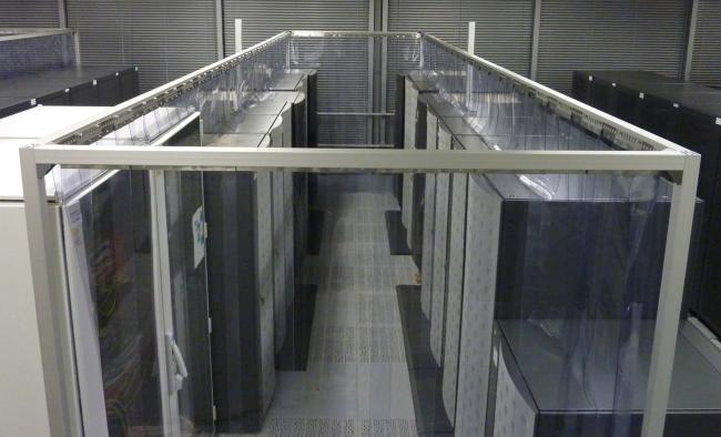 A data center cold aisle containment system using clear PVC strip curtains to control airflow and maintain temperature efficiency.